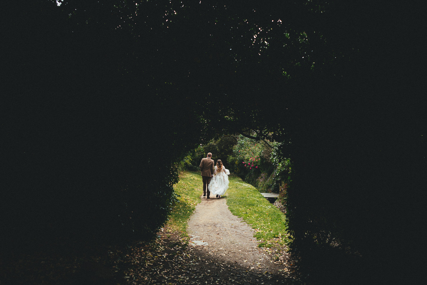 Bride on her way to the church. Bride walking. Pathway. Archway. Cornish Tipi Wedding Photographer. Wedding Photography at Cornish Tipi Weddings on the coast of North Cornwall. Cornish Tipi Wedding is set in a wooded valley, surrounded by ancient woodlands